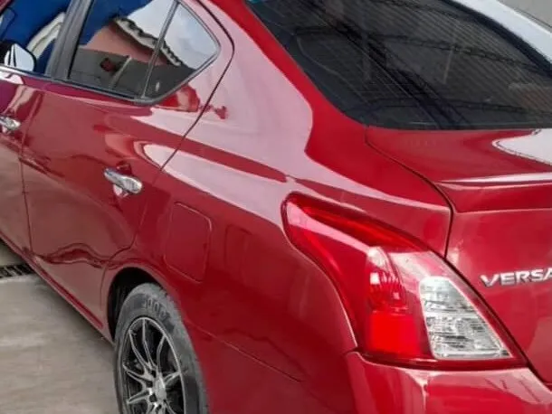 Nissan Versa rojo terminado, con el panel trasero repintado y pulido