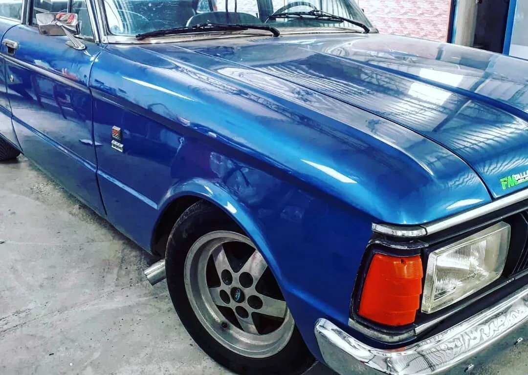 Detalle de la terminación de pintura azul en el guardabarros y el capó de un Ford Falcon reparado en Taller Brenma